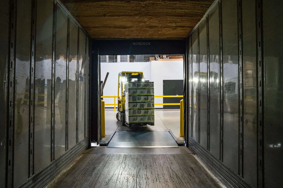 A forklift carrying containers into a warehouse